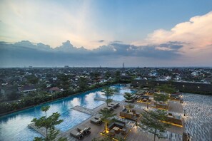 A rooftop pool area with multiple seating zones and a view of the cityscape. - Alila Solo, Java (Surakarta)