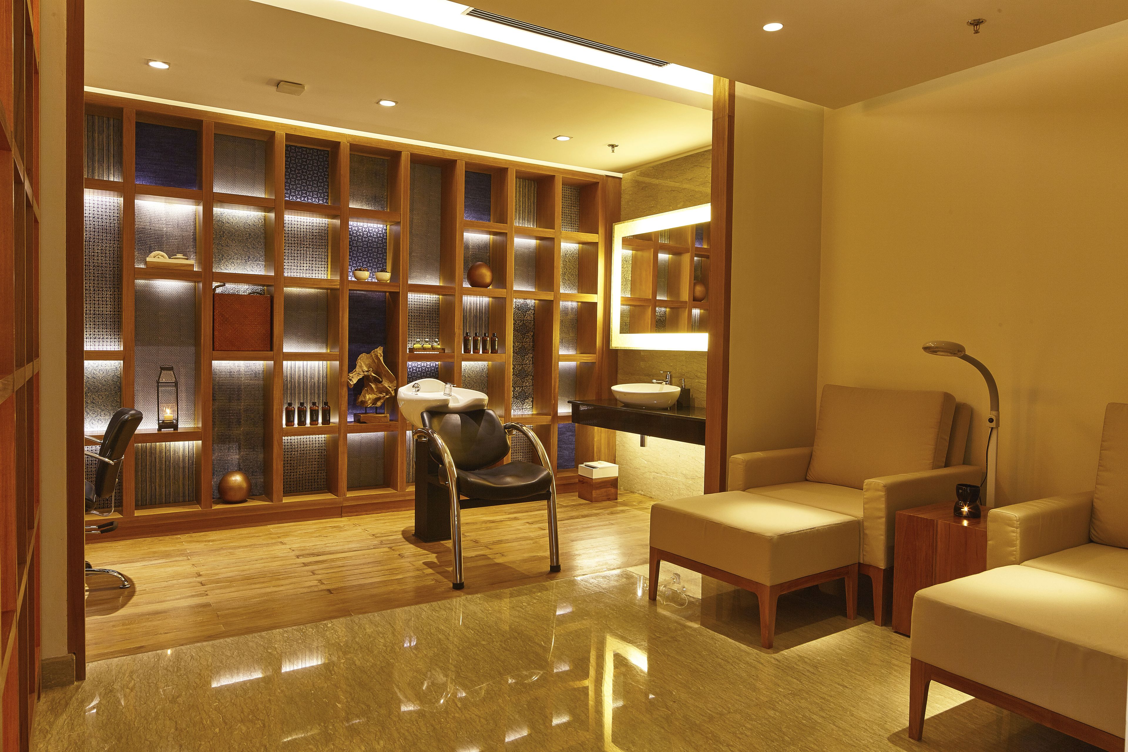 A modern hotel room with a wooden cabinet, a sofa, a chair, and a small table.