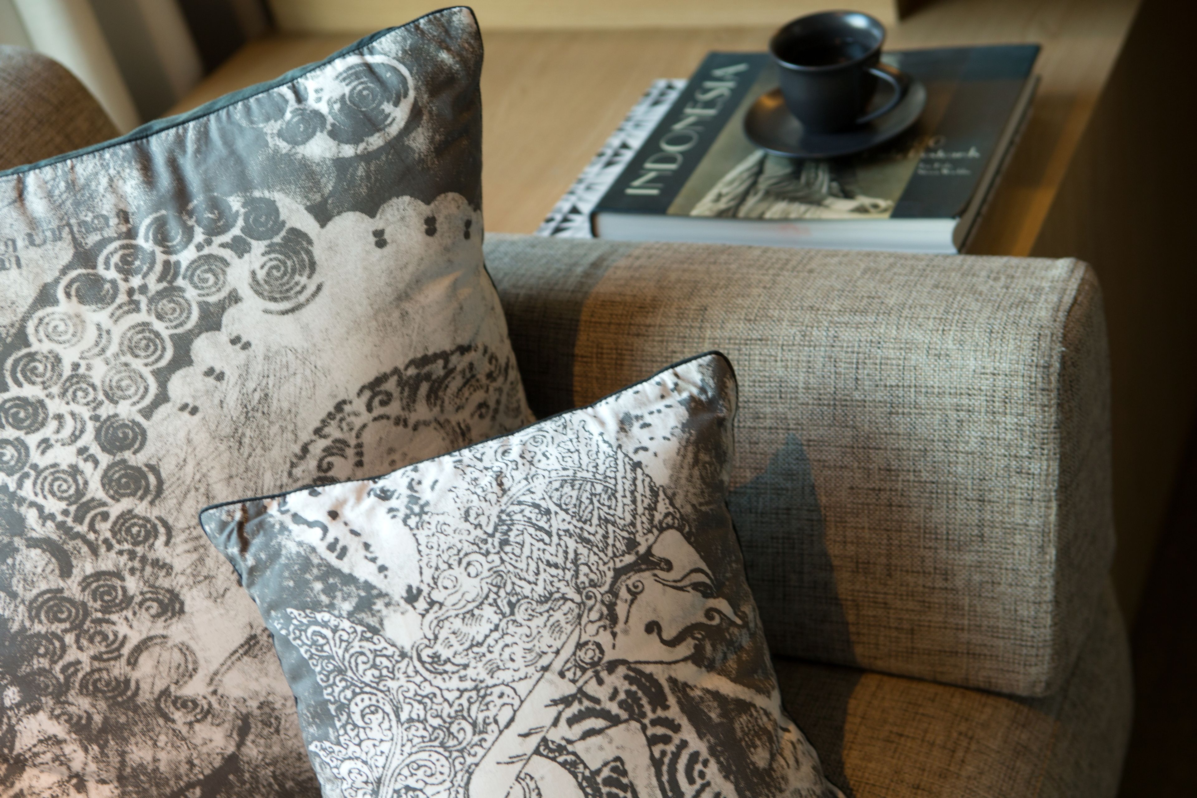A sofa with patterned cushions and a book titled "INDONESIA" on a table beside it.
