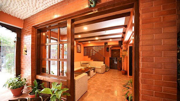 Um hall amplo com parede de tijolos, janelas grandes e área de estar com sofás e mesa de centro.