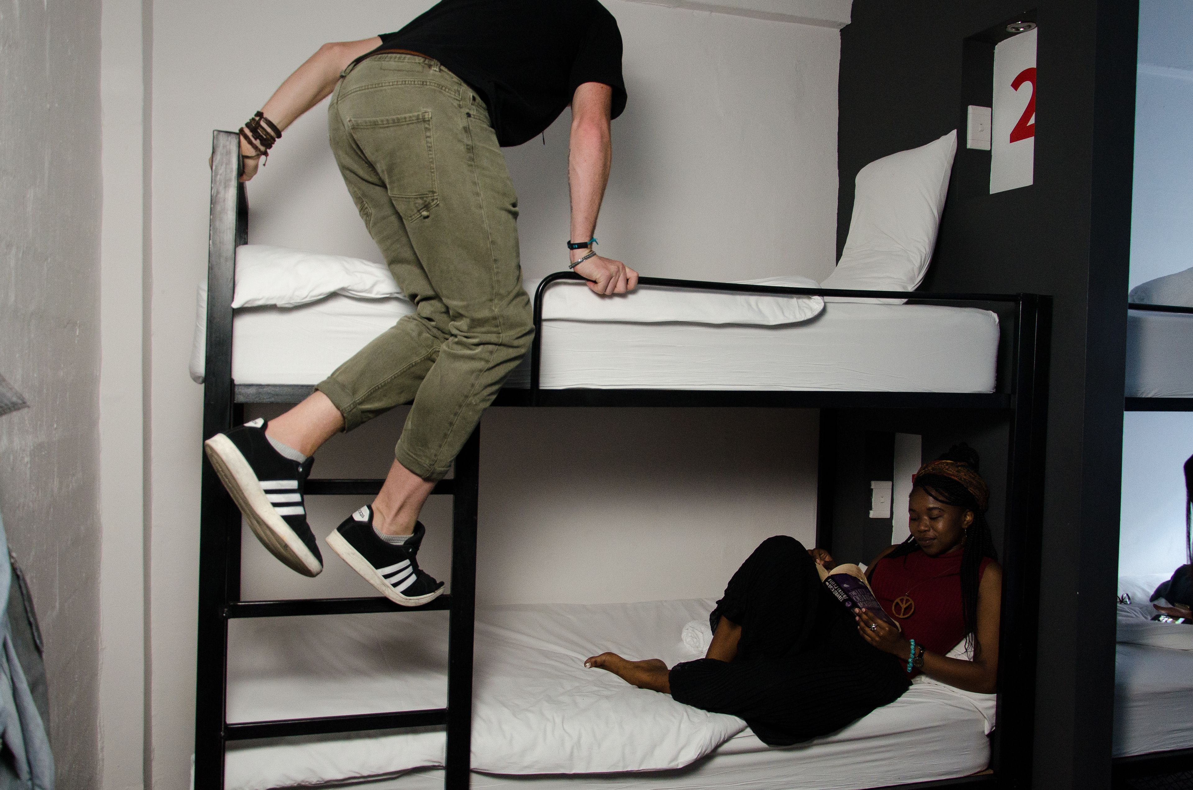 Quarto com beliches, uma pessoa em cima e outra embaixo.