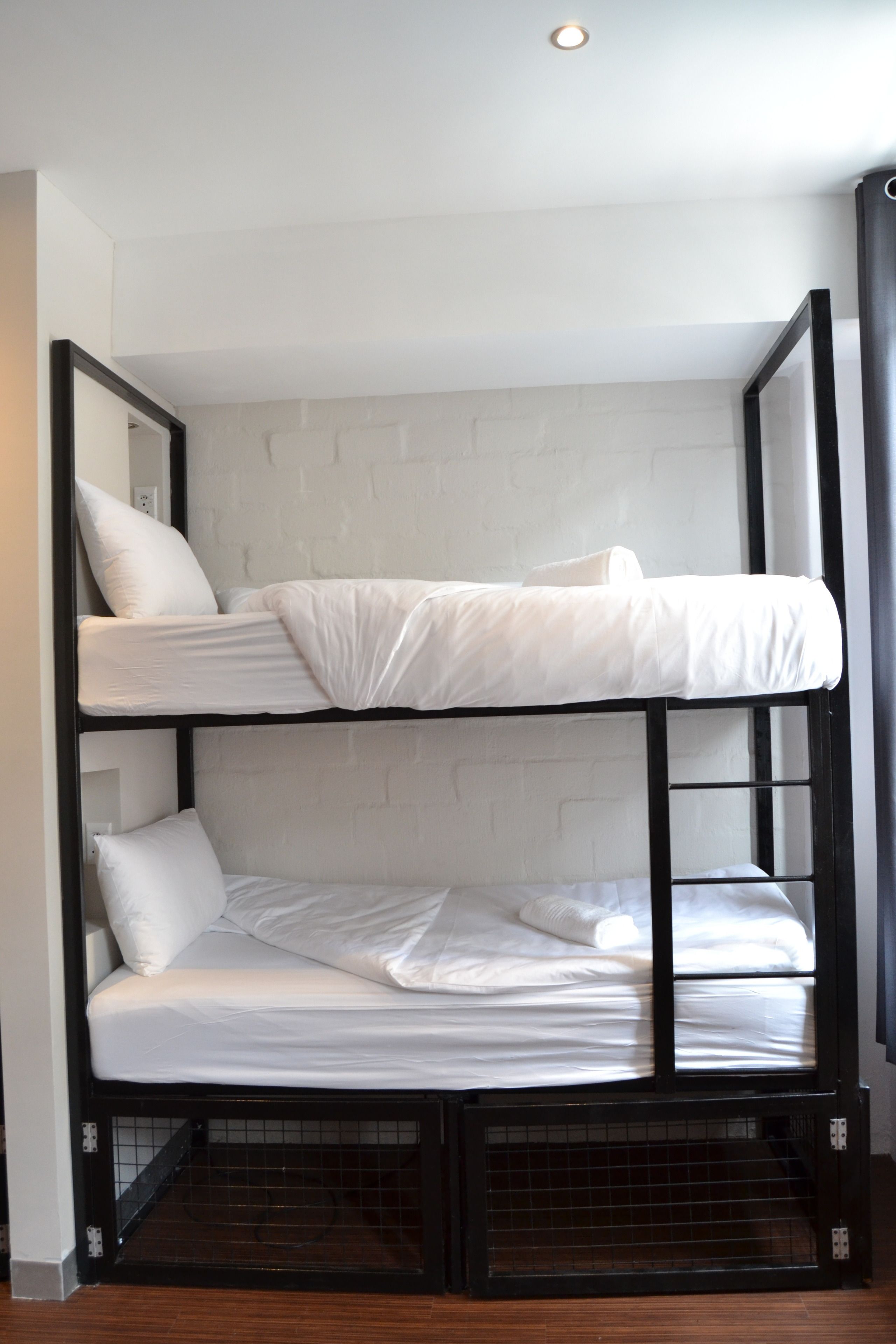 A bunk bed with white bedding, a brick-patterned wall, and a wooden floor.