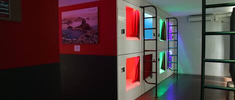 A hotel room with a bunk bed, a red wall, and a cityscape poster.