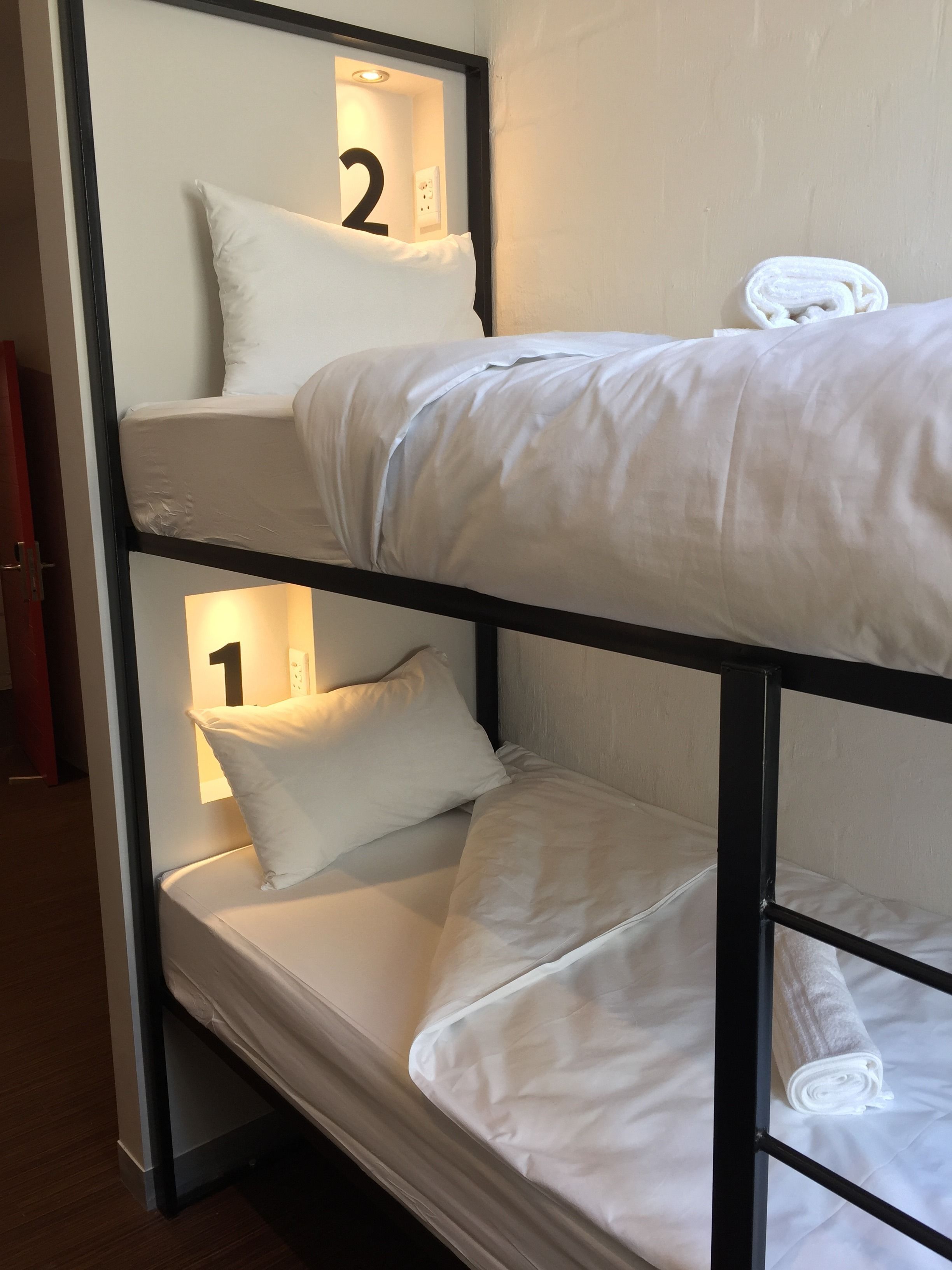 A bunk bed with two levels, each with a pillow and a number sign.