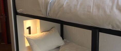 A bunk bed with two levels, each with a pillow and a number sign.