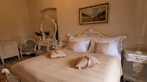 Een slaapkamer met een groot bed, een sierlijk dressoir en een schilderij aan de muur.