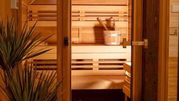Una sauna in legno con panche, un catino e una pianta.