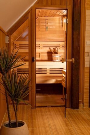 A wooden sauna room with benches, a bucket, and a plant. - LH Hotel Gold (Cesky Krumlov)