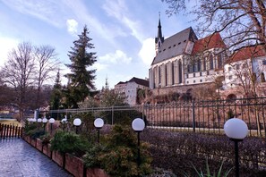 A historic building with a prominent tower, surrounded by a stone wall and a paved walkway. - LH Hotel Gold (Cesky Krumlov)