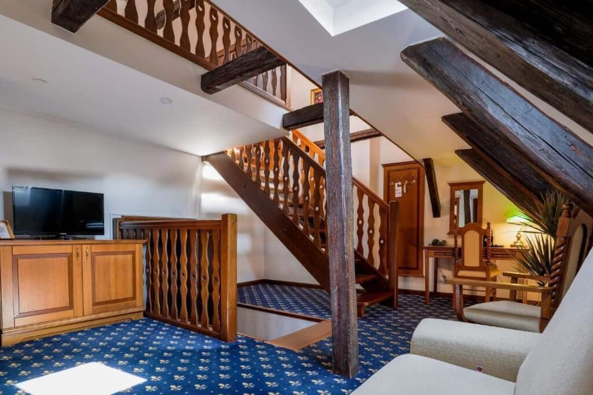Una habitación estilo loft con una escalera de madera, un televisor, un escritorio y una silla.