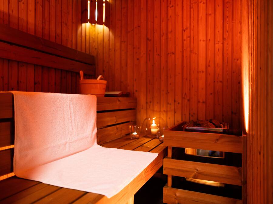 A wooden sauna room with benches and a bench with a towel.