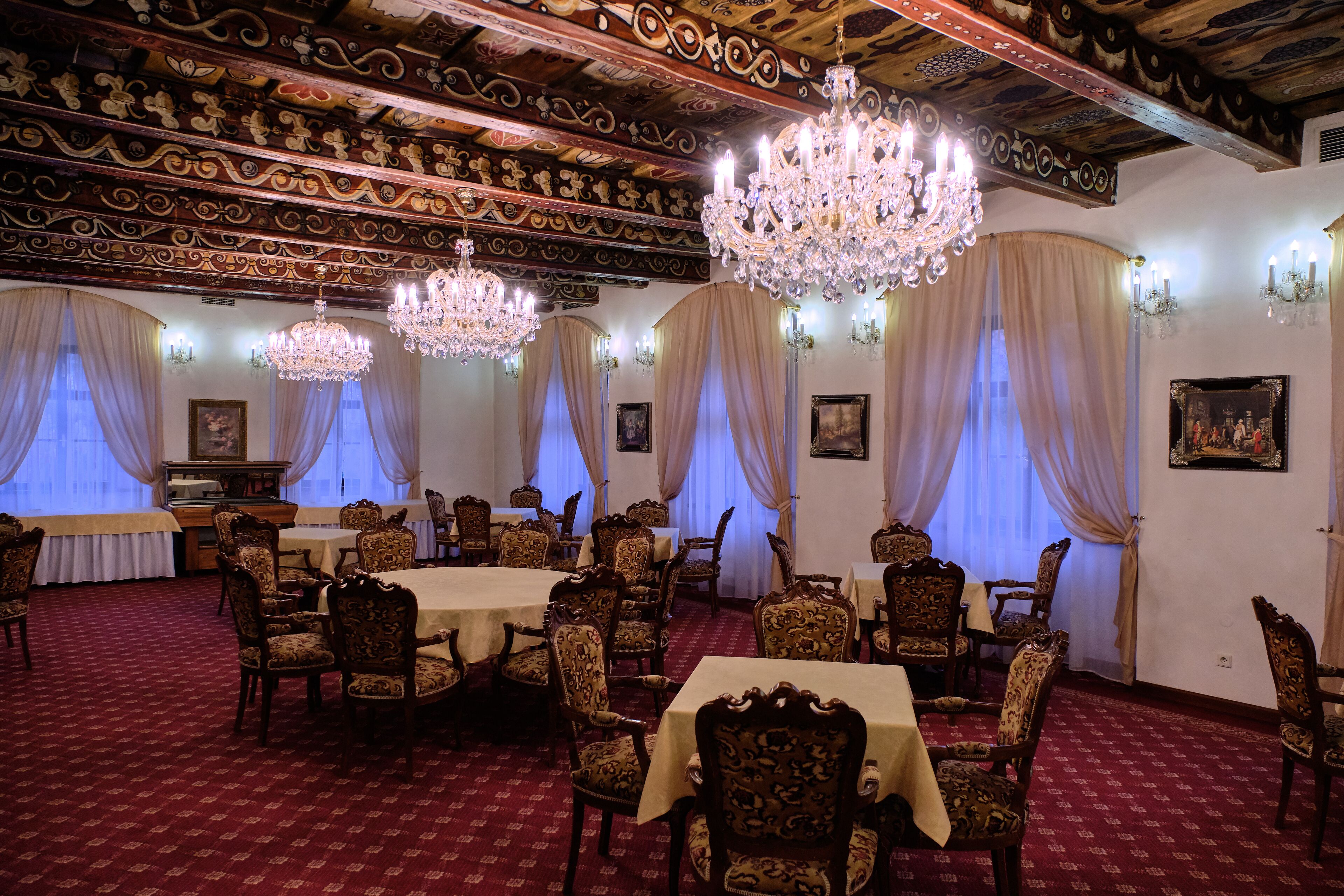A formal dining room with ornate ceiling, chandeliers, and classic furniture.