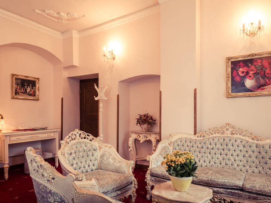 A room with ornate furniture, a desk, a chandelier, and a painting on the wall.