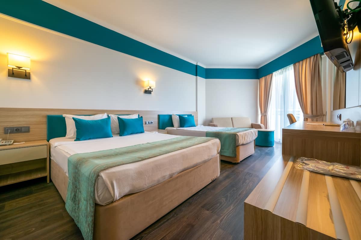 A hotel room with two beds, a desk, and a TV.