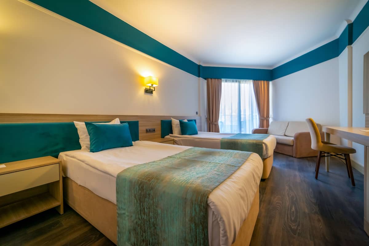 A hotel room with two beds, a desk, and a chair.