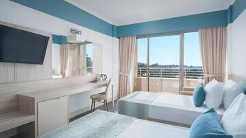 A hotel room with a bed, a desk, a chair, a TV, and a balcony with a view.