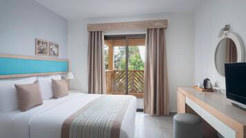 Habitación de hotel con cama, escritorio, televisor y vistas al exterior.