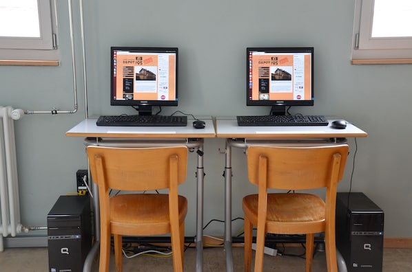 Estación de trabajo con doble monitor, dos sillas, un radiador y dos computadoras de escritorio.