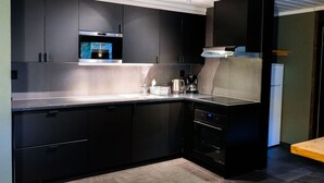 Una cocina moderna con armarios oscuros, electrodomésticos de acero inoxidable y un horno empotrado.