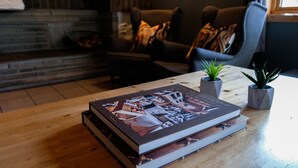 Una sala de estar con chimenea, un sofá y una mesa de centro con un libro y dos plantas en macetas.