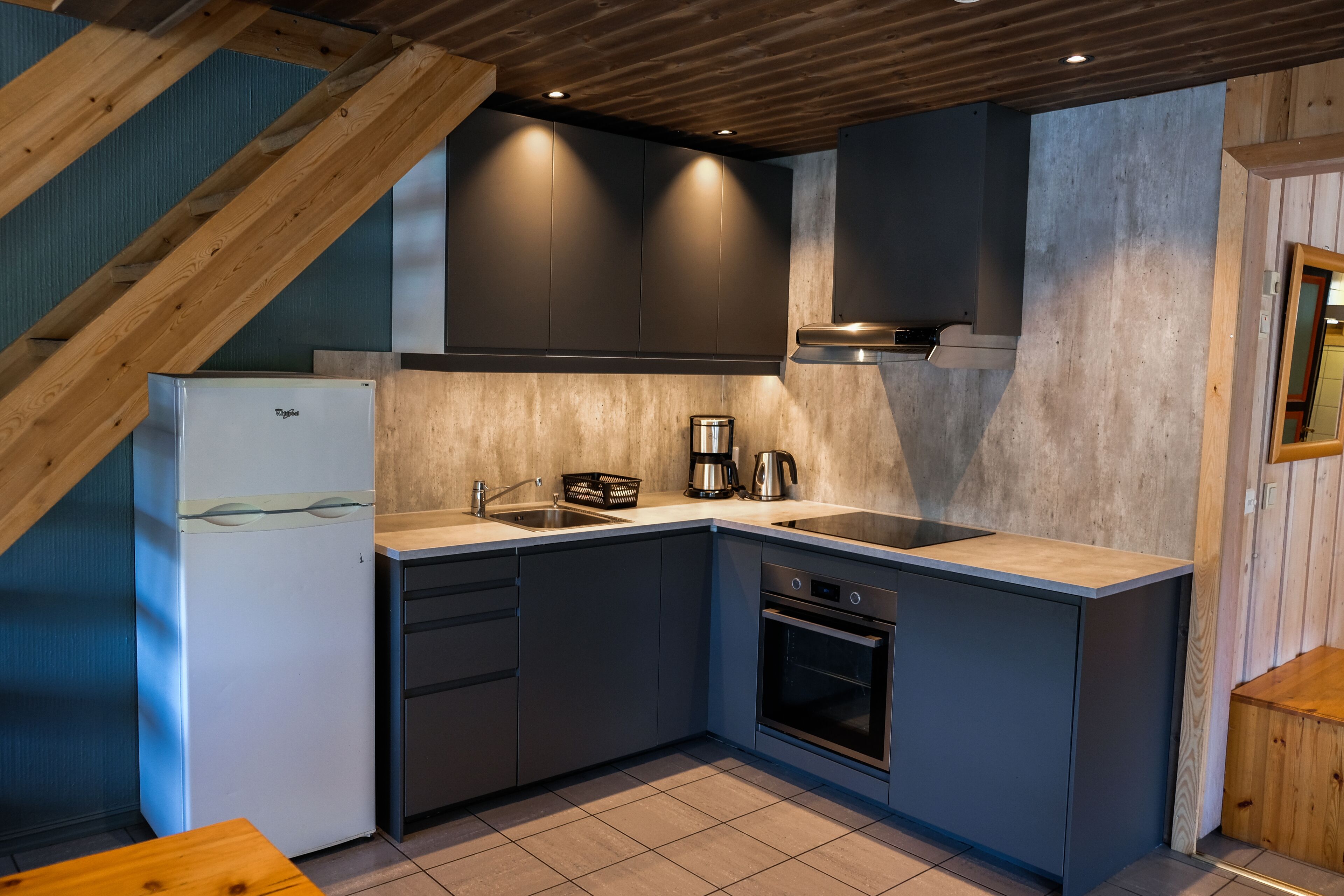 Una cocina compacta con horno integrado, un lavamanos y un refrigerador.