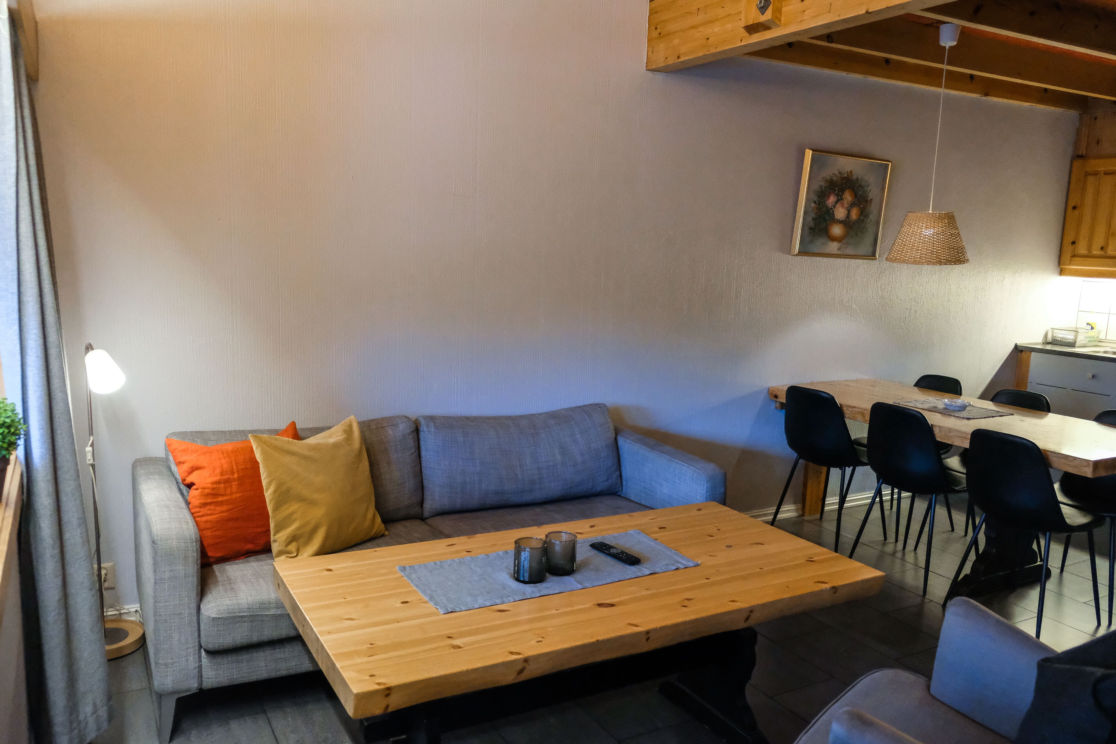 Een moderne woonkamer met een bank, een houten salontafel en een eethoek met stoelen en een tafel.