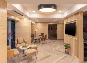 A modern interior with a seating area, a flat-screen TV, and a potted plant. - Ginger Hotel Thane (Thane)