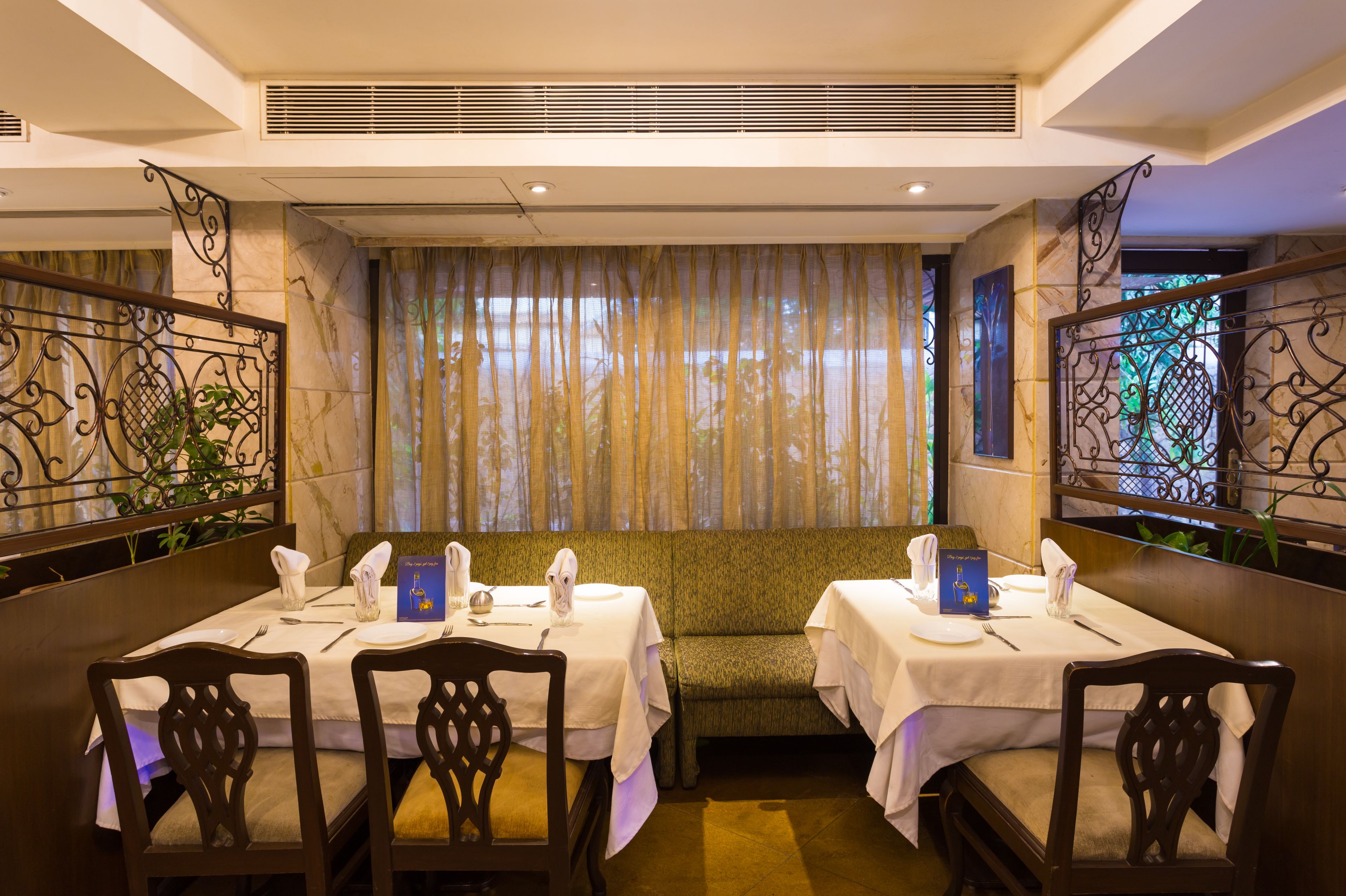 A restaurant with a booth seating arrangement, marble walls, and decorative iron railings.