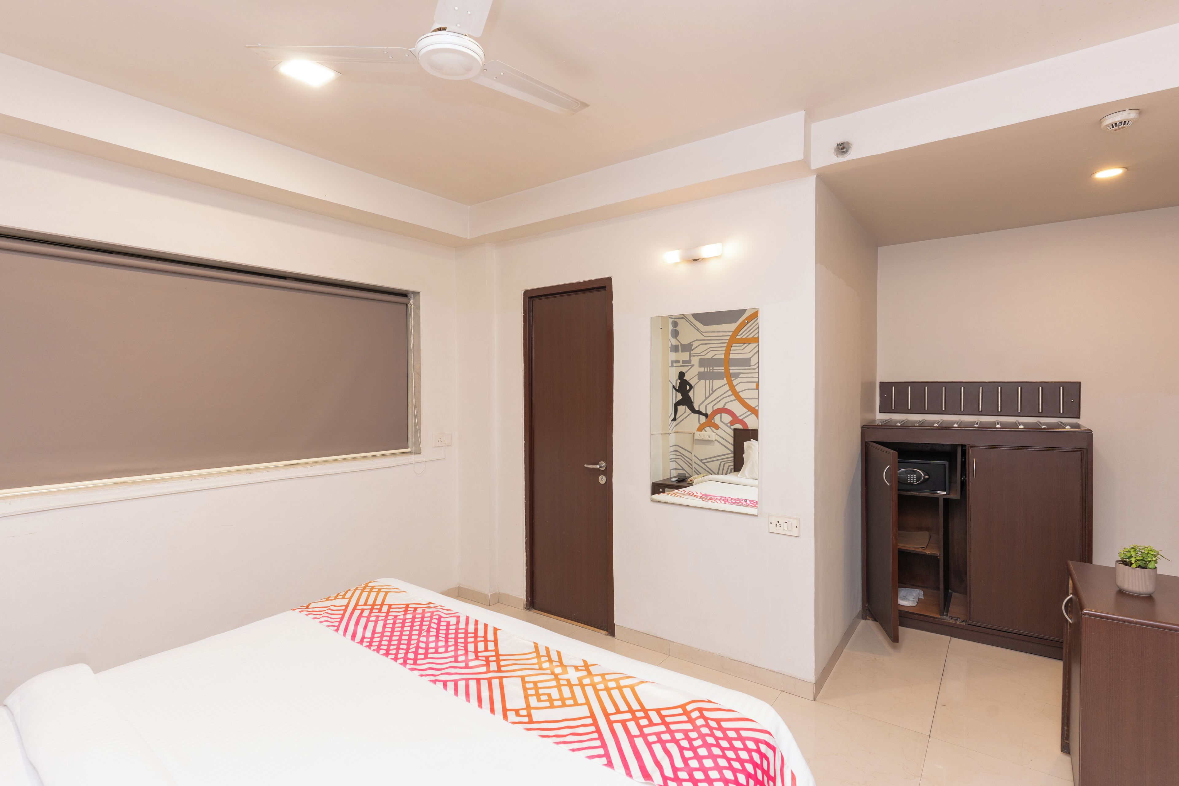 Een slaapkamer met een bed, een kledingkast, een bureau en een plafondventilator.