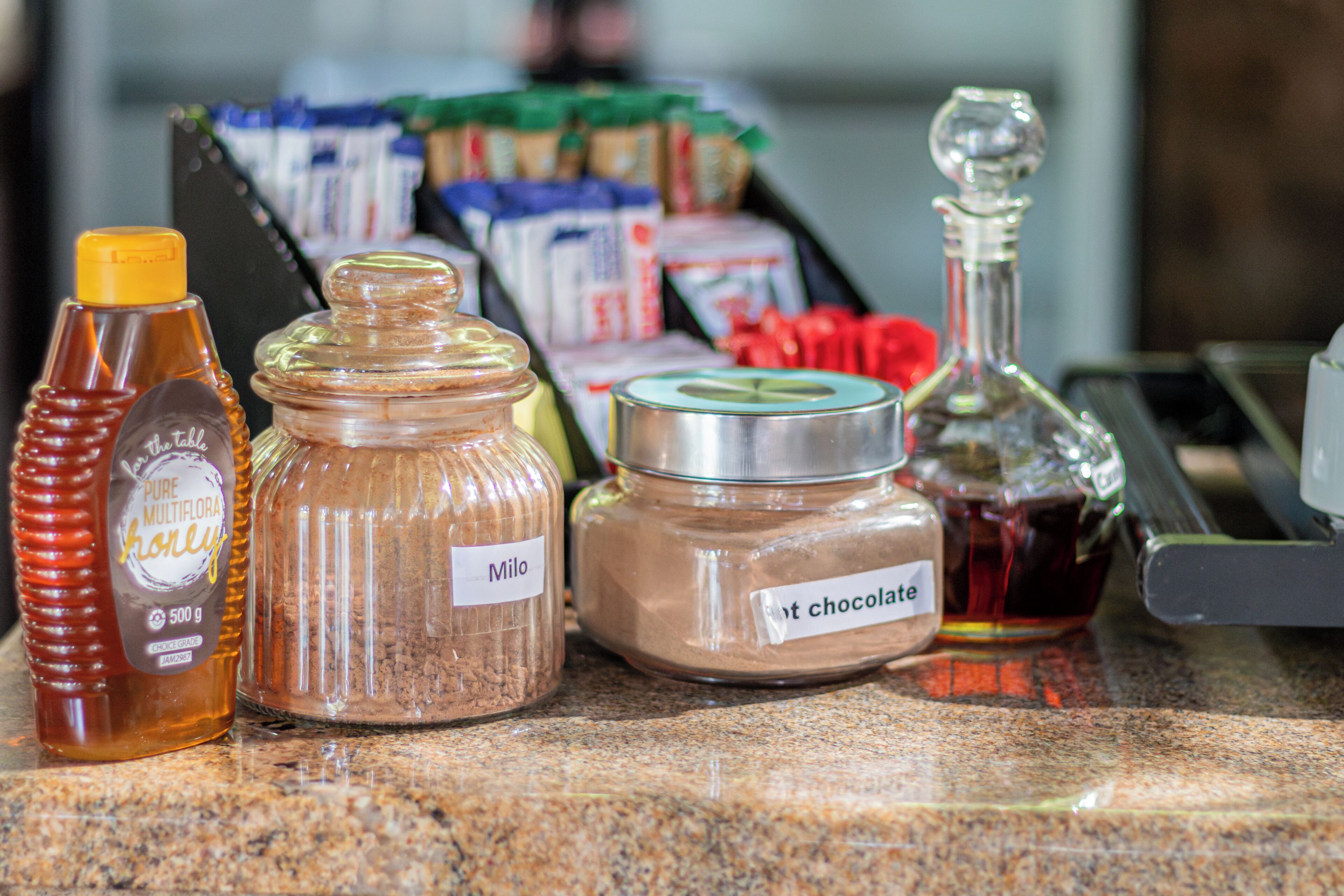 A kitchen counter with various food items including honey, flour, and chocolate.