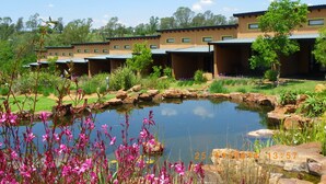 Un hotel con varias unidades, un estanque y zonas verdes circundantes.