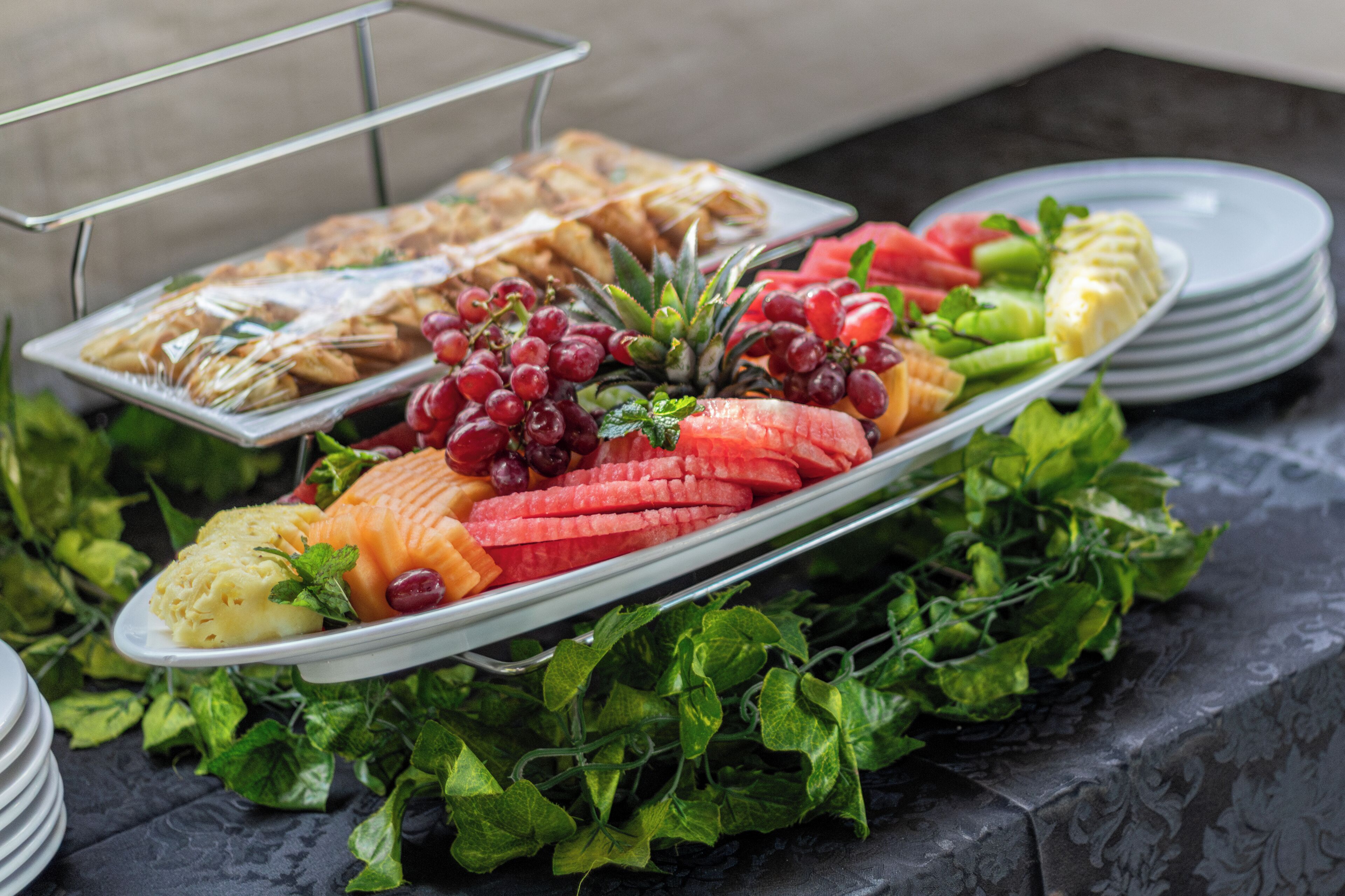 A buffet with various fruits, vegetables, and pastries.