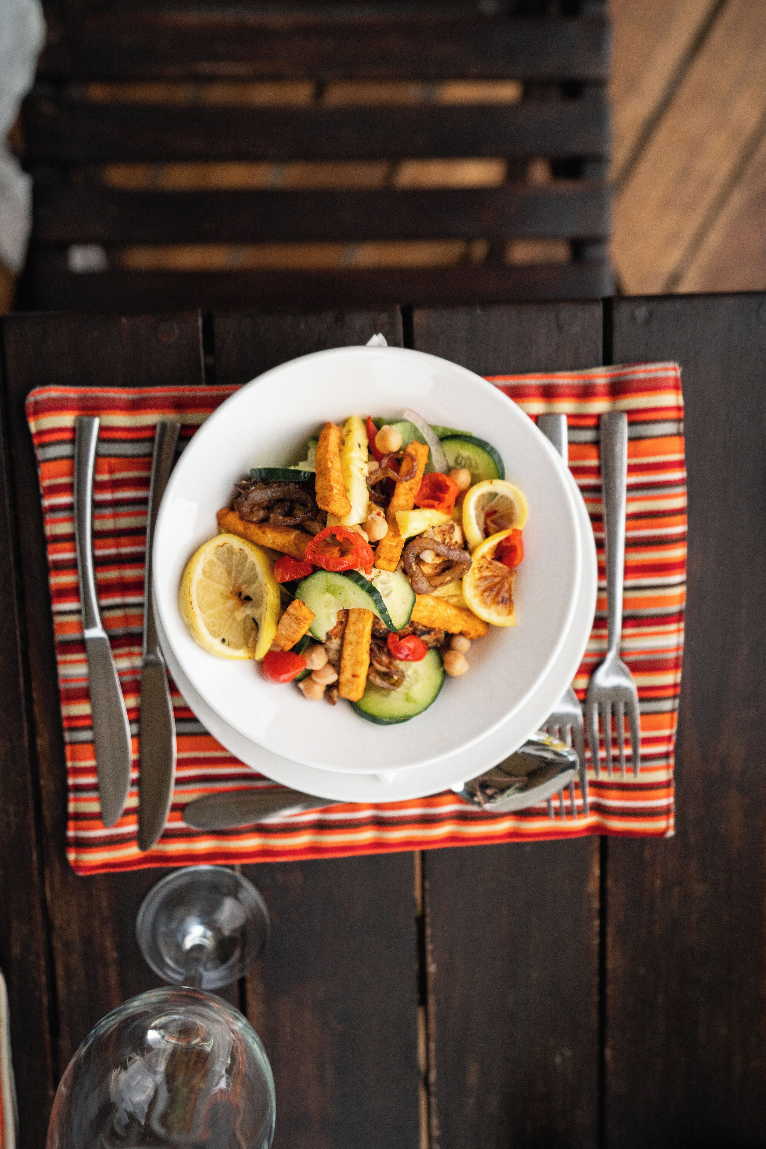 A bowl of food on a table with a striped napkin and cutlery.