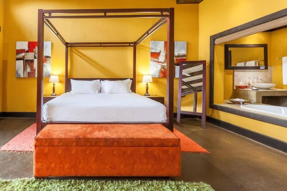 A four-poster bed with white linens, a wooden headboard, and two bedside lamps.