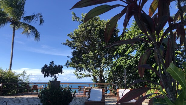 Zona junto a la piscina con sillas de descanso y vista al océano.