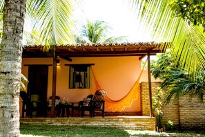 A small house with a porch, a hammock, and a table with chairs. - Pousada Cacimbinha (Tibau do Sul)
