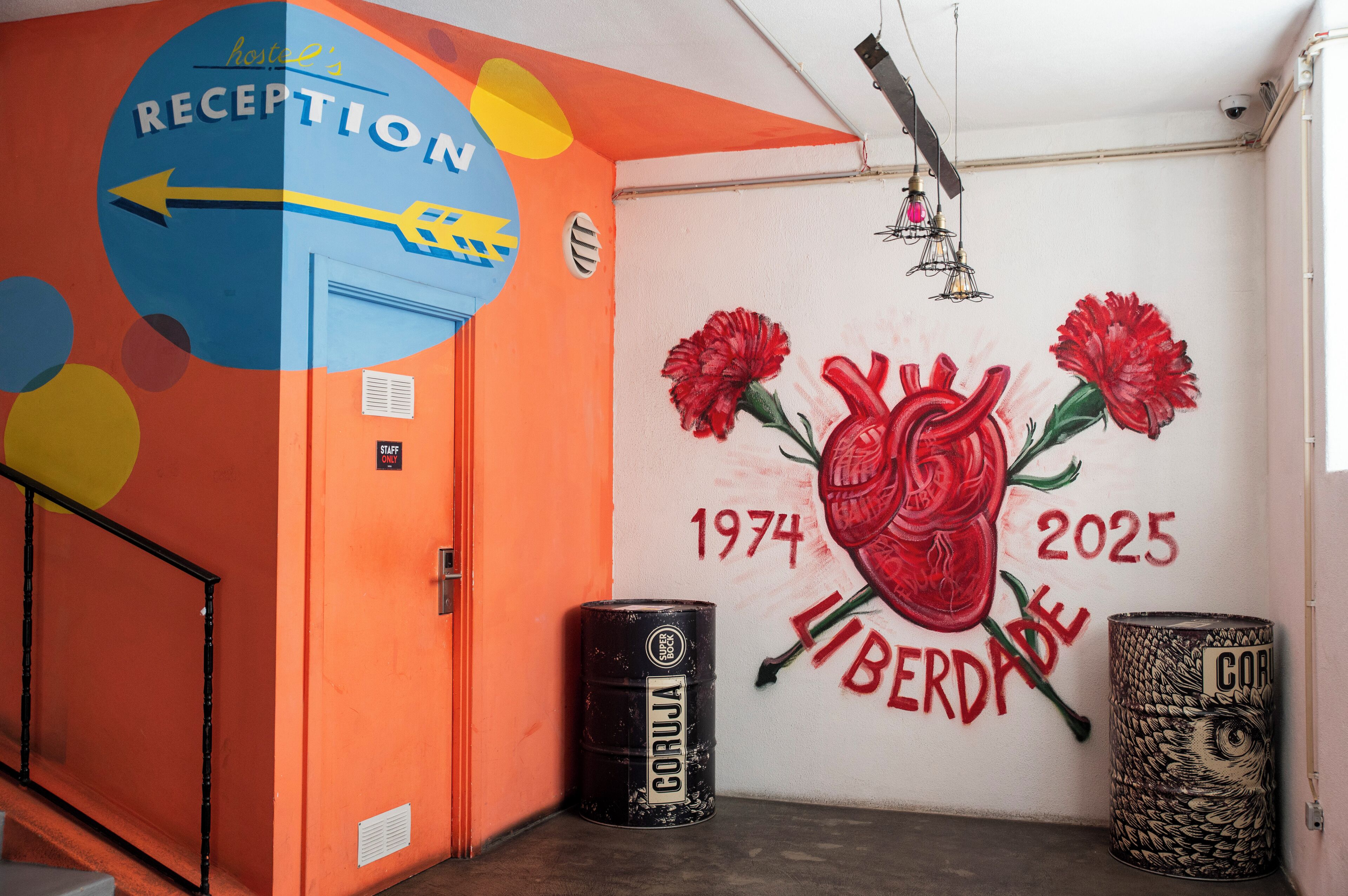 A reception area with a colorful wall mural, a reception sign, and two barrels.