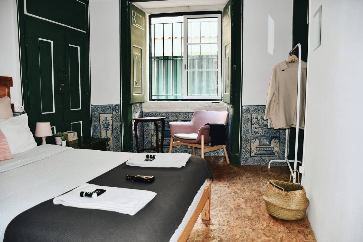 Una habitación de hotel con una cama, una silla, una mesita, una ventana y una puerta.