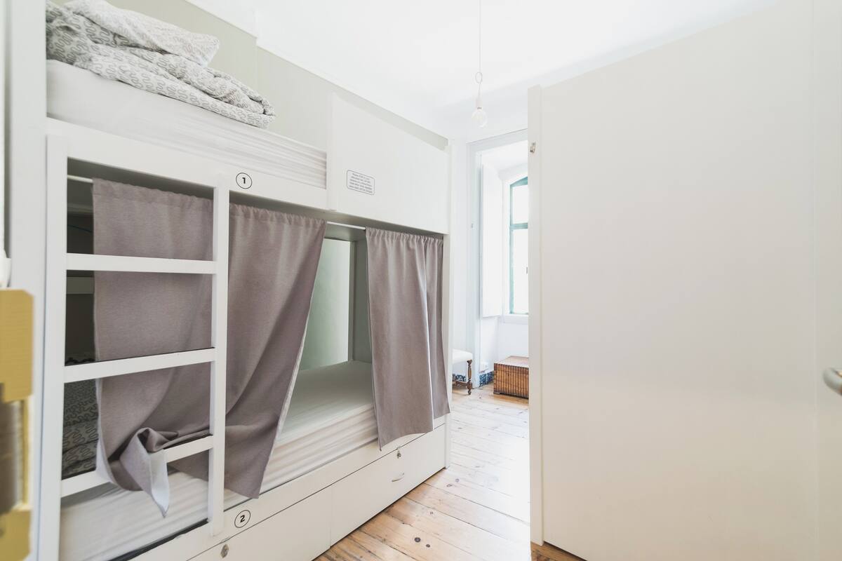 Habitación con literas, ventana, puerta y suelo de madera.