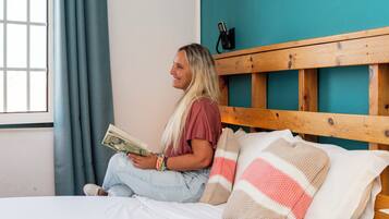 Una persona sentada en una cama con cabecera de madera, sosteniendo un libro.