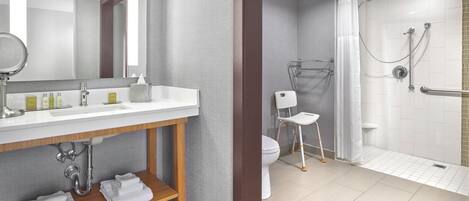 Un baño moderno con un espejo grande, lavamanos blanco y ducha a pie.