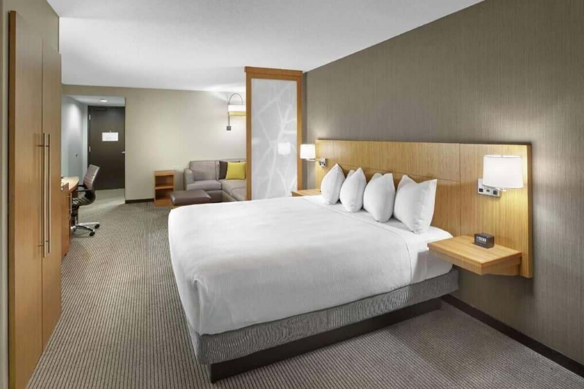 A hotel room with a large bed, bedside tables, a desk, and a chair.
