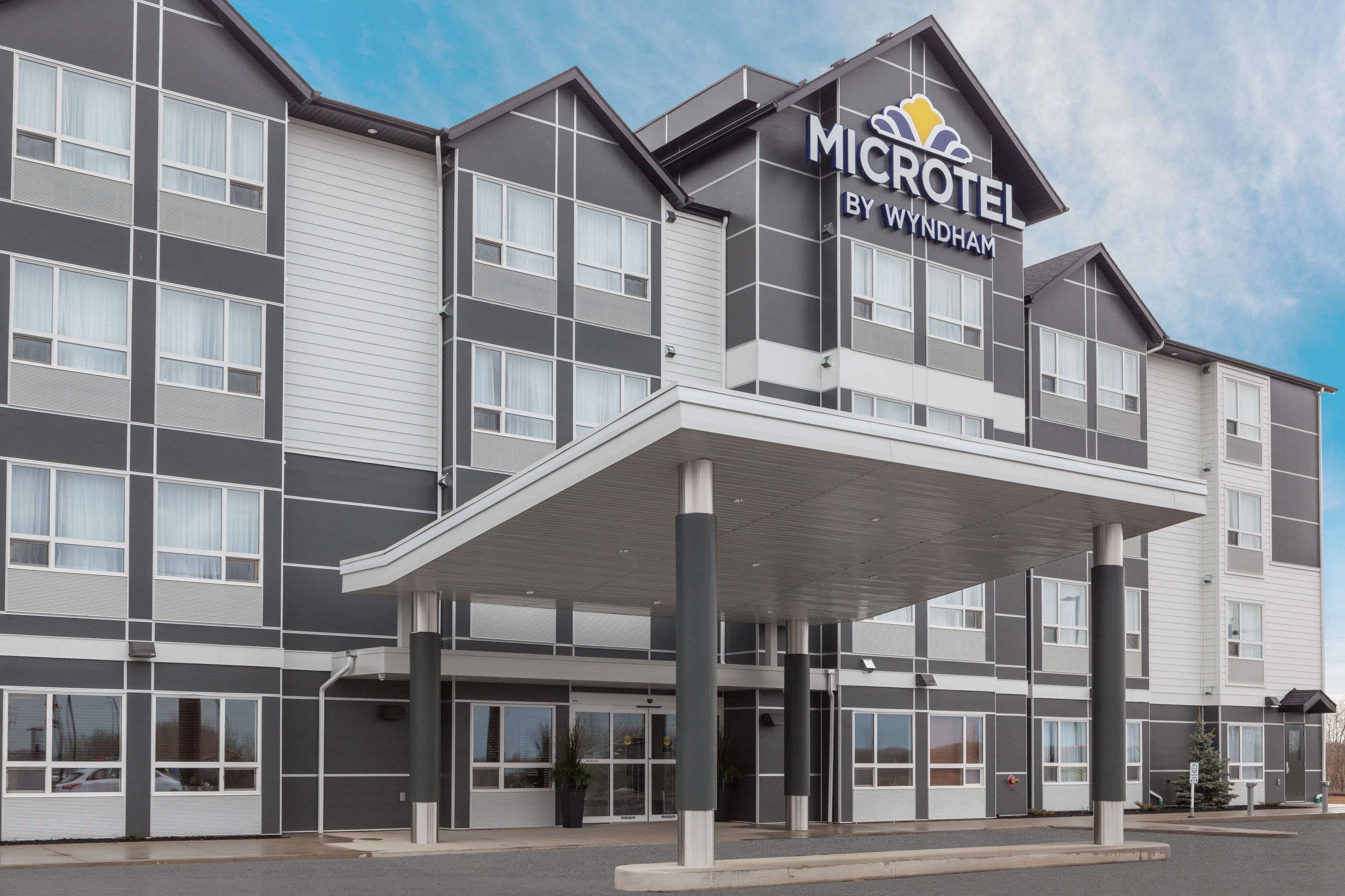 A modern Microtel by Wyndham hotel with a covered entrance, large windows, and a flat roof.