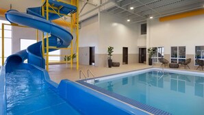 An indoor swimming pool with a blue water slide and a yellow safety structure.
