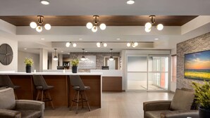 A modern hotel lobby with a reception desk, bar area, and seating.