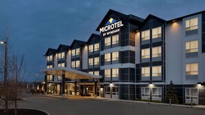 A modern microhotel with a prominent entrance, multiple floors, and a covered outdoor area.