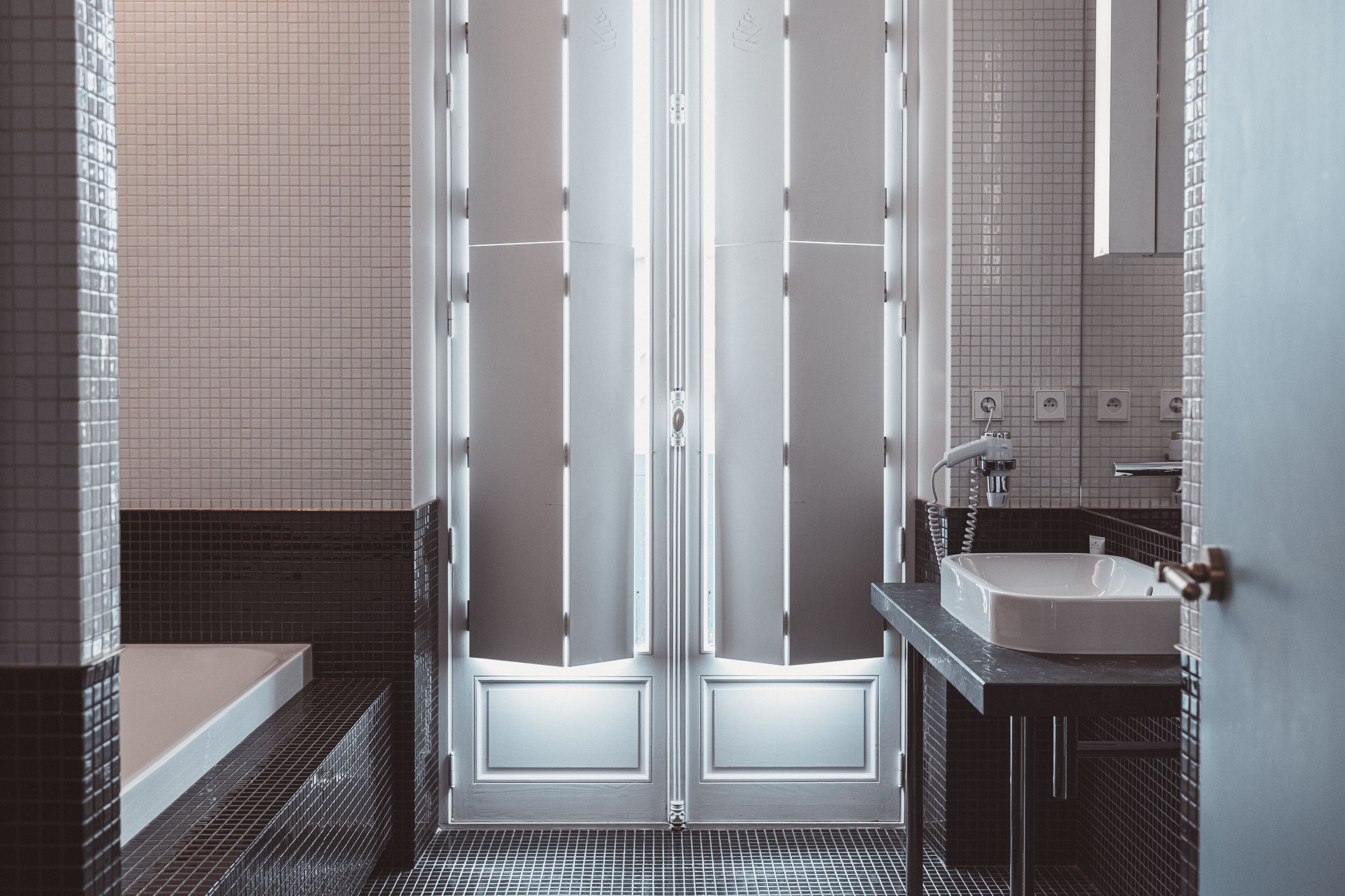 Een moderne badkamer met een dubbele deur, een badkuip en een wastafel.