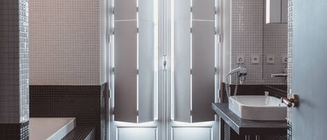 Un baño moderno con puertas dobles, una bañera y un lavamanos.