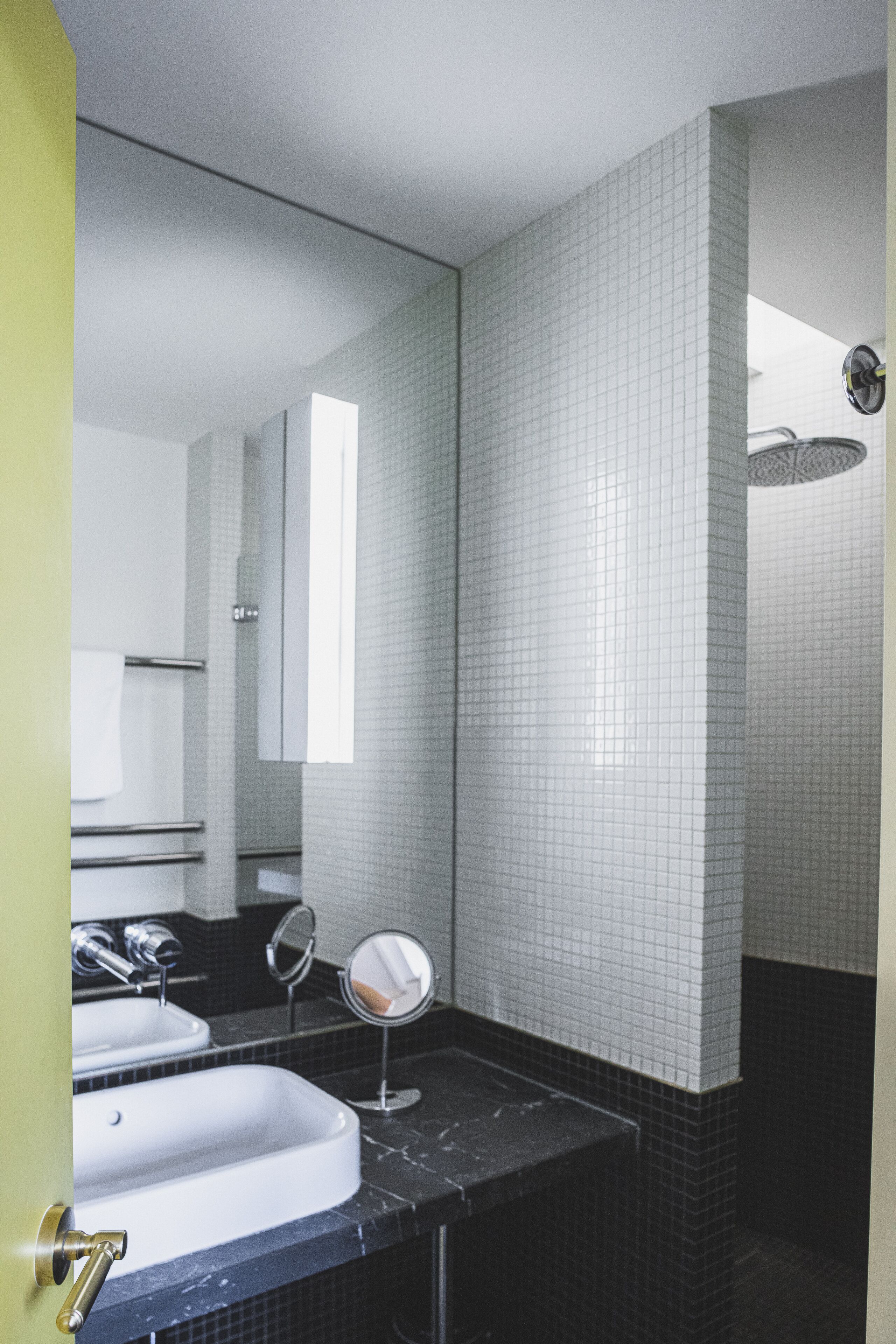 A bathroom with two sinks, a mirror, and a shower.