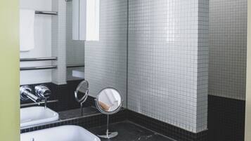 A bathroom with two sinks, a mirror, and a shower.